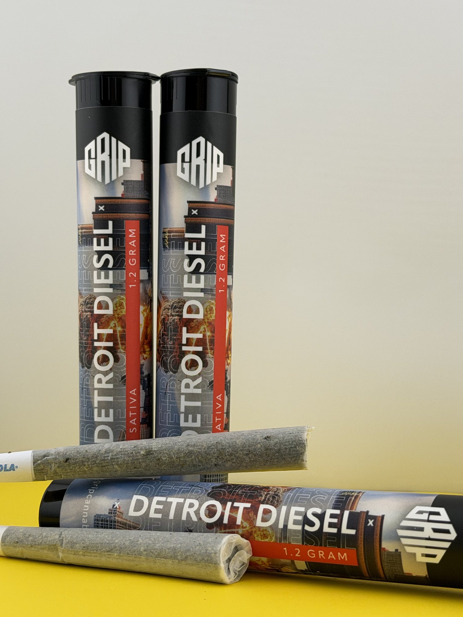 Two Detroit Diesel 1.2 gram pre-roll tubes with rolled joints beside them